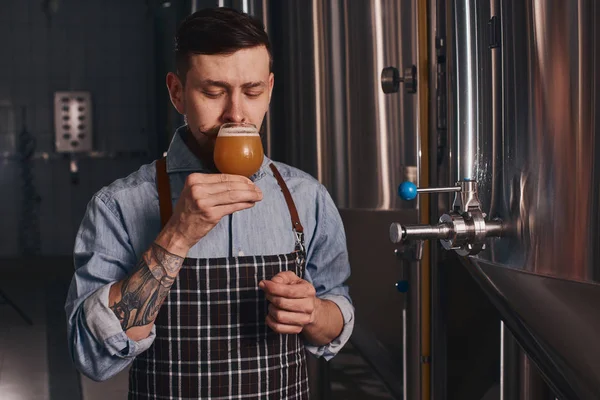 入れ墨された男は、彼が持っているガラスからビールを味わう. — ストック写真