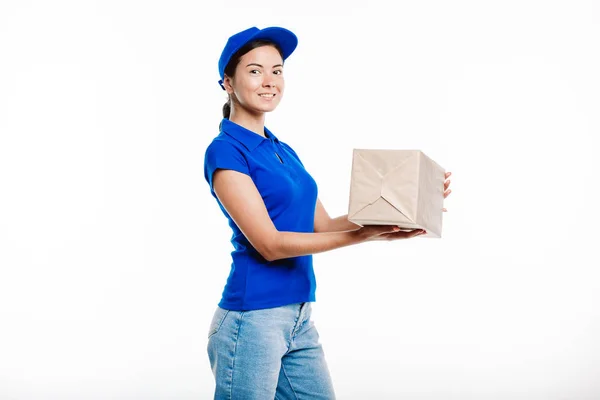 Joven mensajero sonriente mira a la cámara mientras entrega un paquete . —  Fotos de Stock