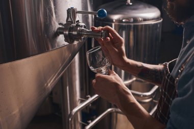 Musluktan bira döken bir barmenin yakın çekim.