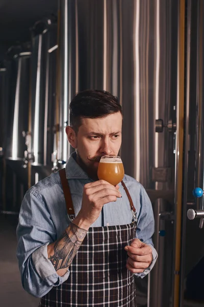Homem trabalhando no bar cheira cerveja no copo . — Fotografia de Stock