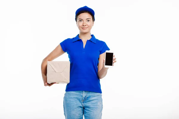 Postangestellte posiert mit Paket und Tablet vor der Kamera. — Stockfoto