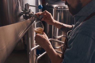 Barmen barda musluktan bira döker.