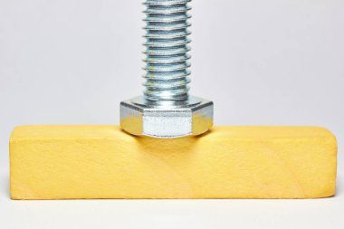 iplik ile metal cıvata ahşap bir çubuk üzerinde yatıyor