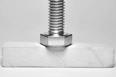 iplik ile metal cıvata ahşap bir çubuk üzerinde yatıyor