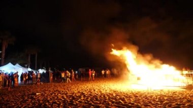 Büyük bir kamp ateşi arka planda bir havai fişek festivali 'nde kalabalığın içinde itfaiye patlama