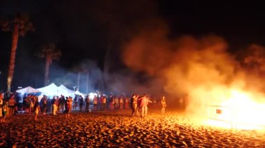 Büyük bir kamp ateşi arka planda bir havai fişek festivali 'nde kalabalığın içinde itfaiye patlama