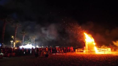 Büyük bir kamp ateşi arka planda bir havai fişek festivali 'nde kalabalığın içinde itfaiye patlama