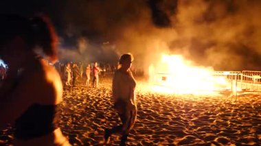 Havai fişek festivali onuruna geceleri plajda büyük bir şenlik ateşi arka planda insanlar bir kalabalık