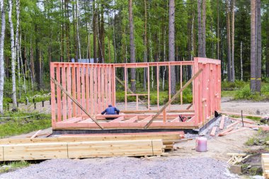 İşçi bir çerçeve inşa eder, çerçevenin ve duvarların montajı, inşaatın başlangıcı. Bir ev inşa etme fikri.