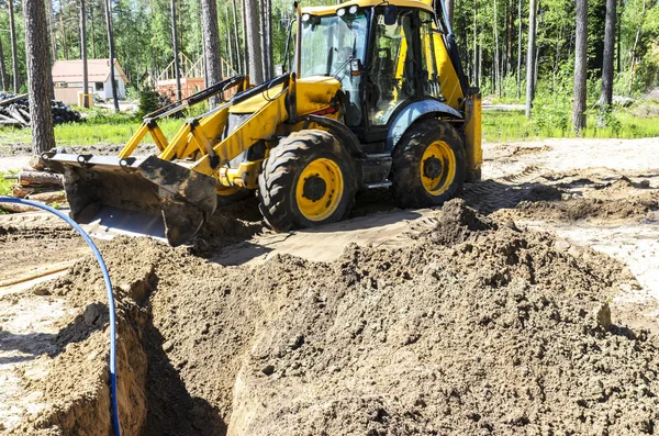traktör kavramı, traktör kazılar ve evin inşaatı için bir orman arsa su döşeme için bir hendek gömer. işçilere yardım.
