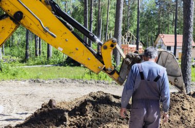 özel evlerin su temini için su kaynağı döşenirken büyük bir iki tekerlekli traktör çalışmaları. bir kır evi inşa kavramı.
