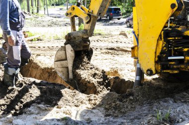 özel evlerin su temini için su kaynağı döşenirken büyük bir iki tekerlekli traktör çalışmaları. bir kır evi inşa kavramı.