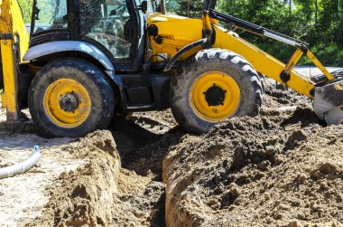 traktör kavramı, traktör kazılar ve evin inşaatı için bir orman arsa su döşeme için bir hendek gömer. işçilere yardım.