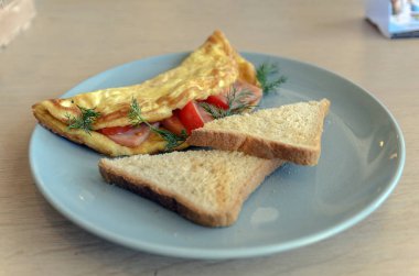 ekmek tost dilimleri ile turkuaz bir tabak üzerinde peynir ve domates ile tavuk yumurtalezzetli omlet.
