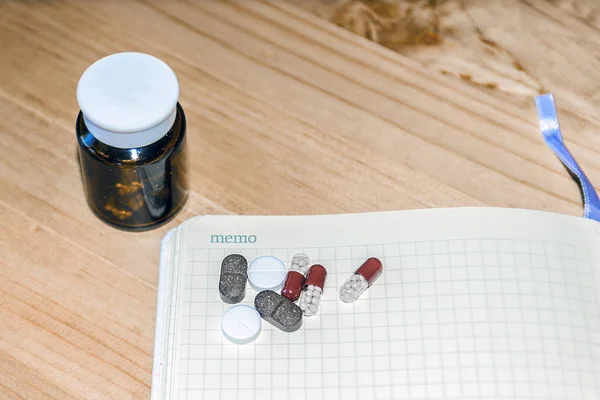 Pills and a white sheet of paper for copy space on wooden background. The view from the top. The concept of minimalism medicine