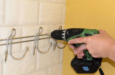 banyo remodeling kavramı. askı, tornavida ile havluluk montajı. işçi bir askı, bornoz ve havlu için kanca asıyor.