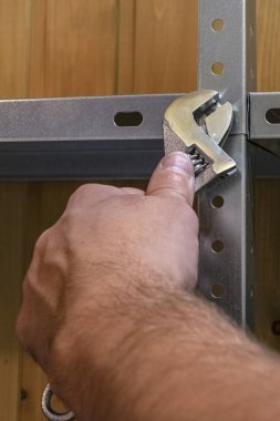 Metal raflar, el emeği, ingiliz anahtarı kullanımı, mekanik montajlar ya da rafları sökmek. Eller çerçevede, dikiz aynasından.