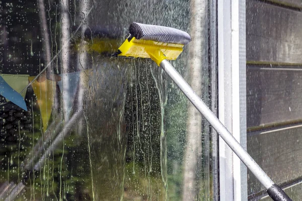 washing Windows, cleaning glasses and surfaces. yellow-white telescopic washing brush cleanly washes and wipes the Windows of the house.