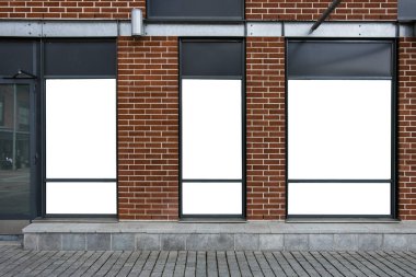 Bir alışveriş merkezinin vitrinindeki reklam panolarına karşı kırmızı tuğladan bir duvar. Mal ve mağazalarınız için cep telefonu reklamları.