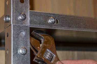 El işi, ingiliz anahtarı ile çalışmak, bir çilingir rafları toplar ya da söker.