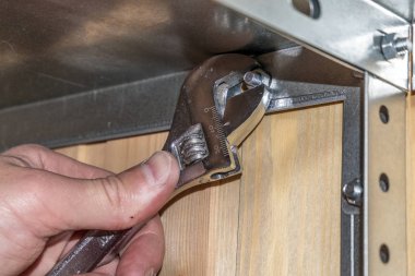 Metal raflar, el emeği, ingiliz anahtarı kullanımı, mekanik montajlar ya da rafları sökmek. Eller çerçevede, dikiz aynasından.