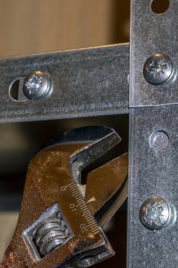 Metal raflar, el emeği, ingiliz anahtarı kullanımı, mekanik montajlar ya da rafları sökmek. Eller çerçevede, dikiz aynasından.