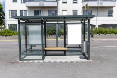 Şehir caddesindeki otobüs durağında iki tane dikey beyaz ilan panosu var. Arka plandaki binalarda ve yolda. Model yap. Güneşli yaz gününde poster.