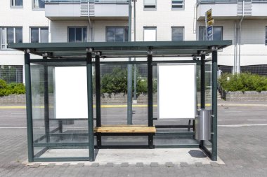 Şehir caddesindeki otobüs durağında iki tane dikey beyaz ilan panosu var. Arka plandaki binalarda ve yolda. Model yap. Güneşli yaz gününde poster.