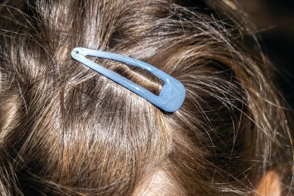 turquoise hair clip in the girl\'s hair, holds the hair and styling on his head.