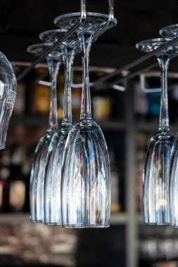 Kafede şampanyalı bardaklar baş aşağı duruyor. İçi cam kadehlerle dolu restoranlar var. Bir barın arka planında alkol şişeleri vardı..