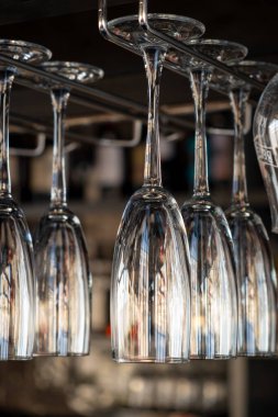 Kafede şampanyalı bardaklar baş aşağı duruyor. İçi cam kadehlerle dolu restoranlar var. Bir barın arka planında alkol şişeleri vardı..