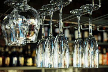Kafelerde şampanyalı, viskili ve konyaklı bardaklar baş aşağı duruyor. Restoranların içinde de uzatılmış cam ve yuvarlak bardaklar var. Bir barın arka planında alkol şişeleri vardı..