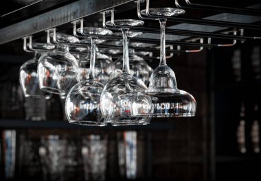 Bir kokteyl, viski ve konyak bardakları kafelerde baş aşağı duruyor, restoranların içleri uzatılmış cam ve yuvarlak bardaklarla dolu. Bir barın arka planında alkol şişeleri vardı..