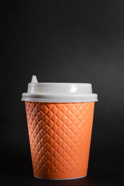 Siyah arka plan kahve fincanı, tek kullanımlık turuncu bardak.