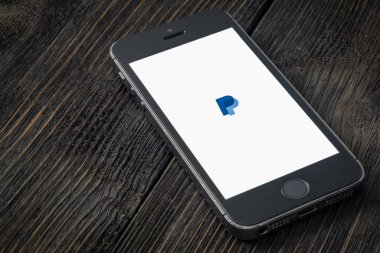 Rusya, St. Petersburg, Nisan 2020: Paypal, ABD 'li çevrimiçi ödeme ve bankacılık hizmetleri şirketidir. Ekranda PayPal uygulamaları olan Apple iPhone tahta bir arka planda yatıyor.