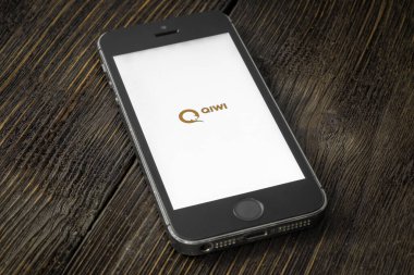 Rusya, St. Petersburg, Nisan 2020: QIWI - Rus çevrimiçi ödeme ve bankacılık hizmetleri şirketi. Ekranda qiwi uygulamaları olan Apple iPhone tahta bir arka planda yatıyor