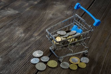 Çeşitli değerlerde bozuk paralarla dolu bir alışveriş arabası. Uluslararası kriz; para biriminin değer kaybı ve krizin soyutlanması.