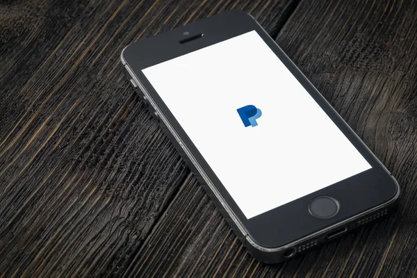 Rusya, St. Petersburg, Nisan 2020: Paypal, ABD 'li çevrimiçi ödeme ve bankacılık hizmetleri şirketidir. Ekranda PayPal uygulamaları olan Apple iPhone tahta bir arka planda yatıyor.