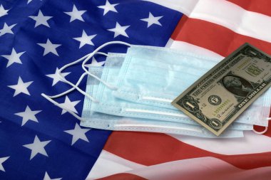 Amerikan bayrağının önünde sağlık maskeleri üzerinde duran bir Amerikan doları.. 