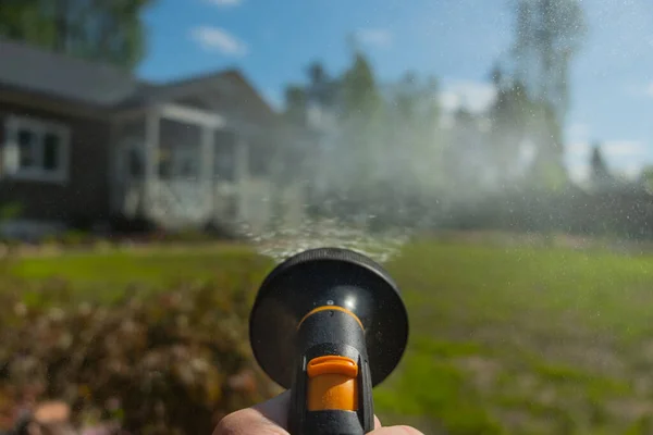 あなたの手の中に花 庭や野菜の庭のための散水ツール 噴霧器 美しい木造住宅を背景に庭や芝生に水をやるプロセス — ストック写真