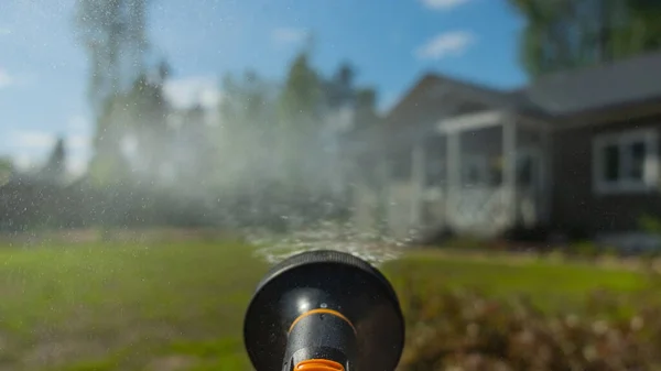 庭の道具の水やり缶から脱出する水のジェットは 家と庭の若い新鮮な芝生 朝の背景に 庭や芝生に水をやるとき — ストック写真
