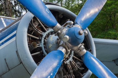 Motorun kompartımanına yakın çekim ve asfaltta güneşli bir günde eski bir uçağın pervanesi.