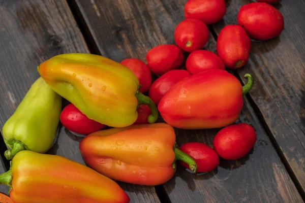 juicy ripe bell peppers and red tomatoes lie on the surface of the wooden floor, terrace. wash food in the fresh air.