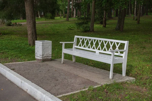 Parkta çöp tenekesi olan beyaz bank..