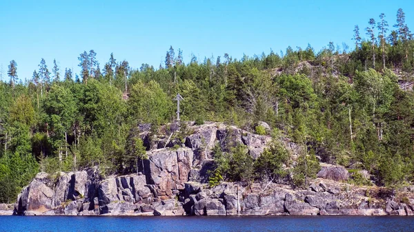 Güneşli bir günde sudan çıkan mavi sular ve ağaçlarla kaplı kayalar, Ladoga Gölü 'ndeki Valaam Takımadaları' nın güzel adaları, Rusya, Karelia.