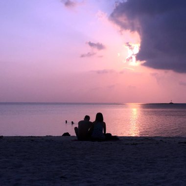 Zen sahilinde birlikte bali, Endonezya'da pembe gün batımını izleyen bir çift. 