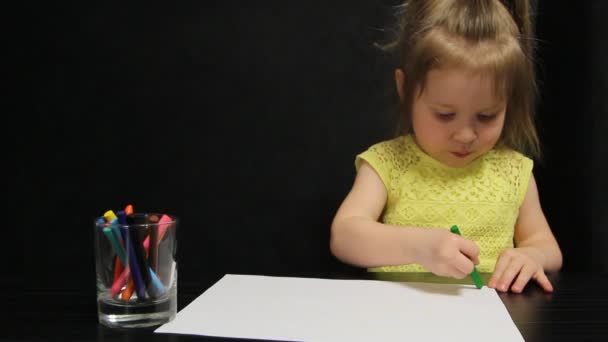Маленька дівчинка малює зеленим олівцем на папері — стокове відео