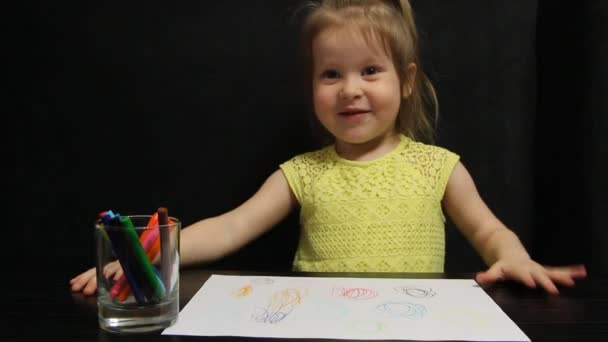 Маленька дівчинка посміхається і маскується під час малювання — стокове відео