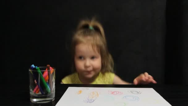 小さな女の子は紙の上に彼女の絵を示しています — ストック動画
