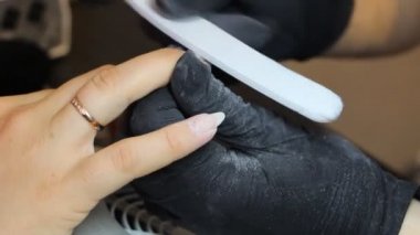 Manikürcü güzellik salonunda bir manikür için tırnak çubuğu öğütür. Tırnak tedavisi, taşlama ve parlatma.